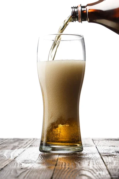 Frosted glass of light beer on wood table and white background behind