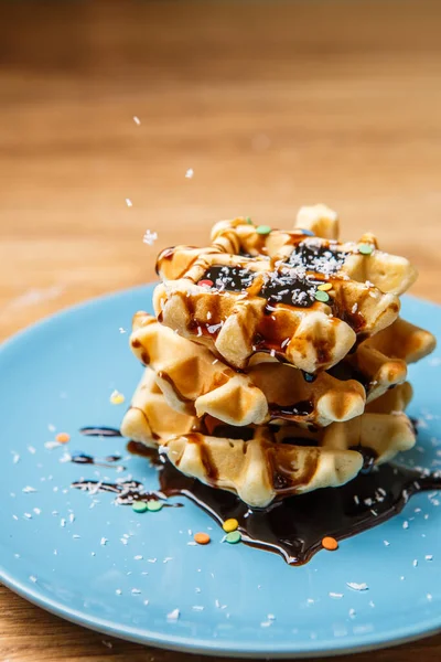 Ev yapımı waffle Çikolata ve hindistan cevizini mavi tabağa serpiyor