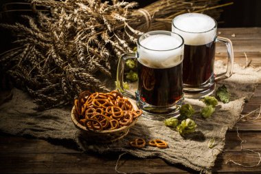 Buğday ve zıpzıp dolu iki tankard birası, ahşap masada bir sepet kraker.