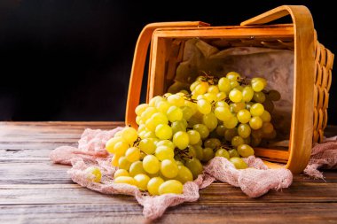 Masada yeşil üzümlü ahşap sepet resmi ve siyah arka planda kumaş.
