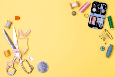 Kompozisyon konuları ve dikiş aksesuarları - makas, santimetre, sarı zemin üzerine sabitler. İğne işi ve terzilik için kavram