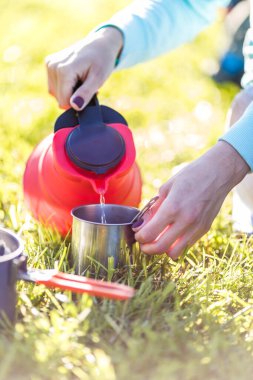 Turistler açık havada çaydanlıktan su döker.