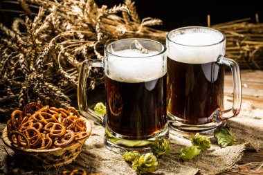 Zıplayan bira bardağı ve ahşap masada keten kumaş üzerinde kraker.