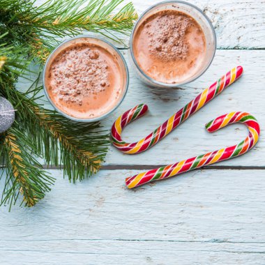 Beyaz ahşap arka planda oyuncakları olan iki bardak kakao ve noel ağacı. Yukarıdan görüntüle