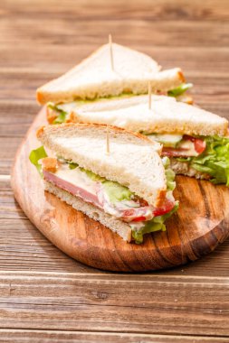 Tahtanın üzerinde kürdanlı ve taze sebzeli hamburgerler.