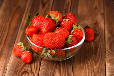 Tahta masadaki fincanda taze olgun çilek resmi