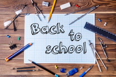 Yazılı grafik kağıdı, okula dönüş ve ahşap masadaki öğrenci materyali. Üst görünüm