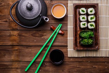 Çaydanlık çay, rulo, yemek çubukları ahşap yüzeyde