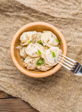 Et hamuru - Rus pelmeni, ahşap bir tabakta etli ravioli ve peçete.