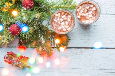 İki bardak marşmelovlu kakao ve beyaz ahşap arka planda oyuncakları olan Noel ağacı. Yukarıdan görüntüle