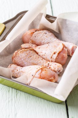 Beyaz ahşap masada çiğ tavuk budu.