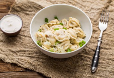 Et hamuru - Rus pelmeni, ahşap arka planda beyaz tabakta etli ravioli.