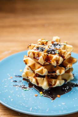 Ev yapımı waffle Çikolata ve hindistan cevizini mavi tabağa serpiyor