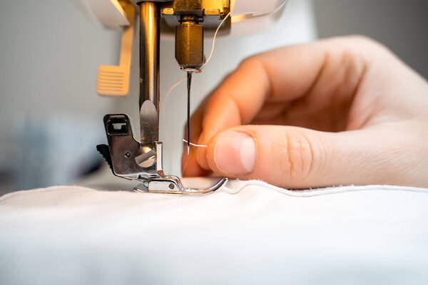 Закрыть швейную машинку и предмет одежды. Концепция для шитья и пошива
