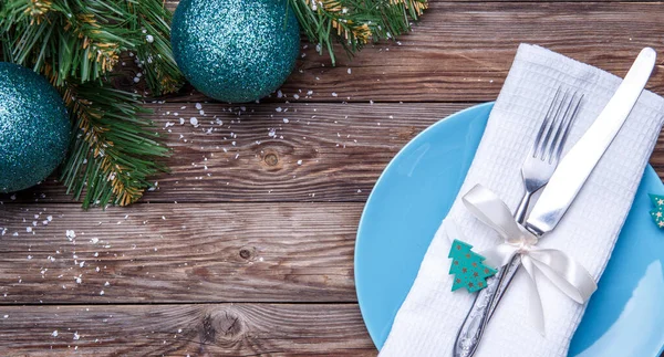 圣诞餐桌摆设为蓝色的盘子 叉子和刀 装饰过的缎带和带有冷杉玩具的蝴蝶结 白色餐巾和带有圣诞球的圣诞松树枝条 圣诞节背景 — 图库照片