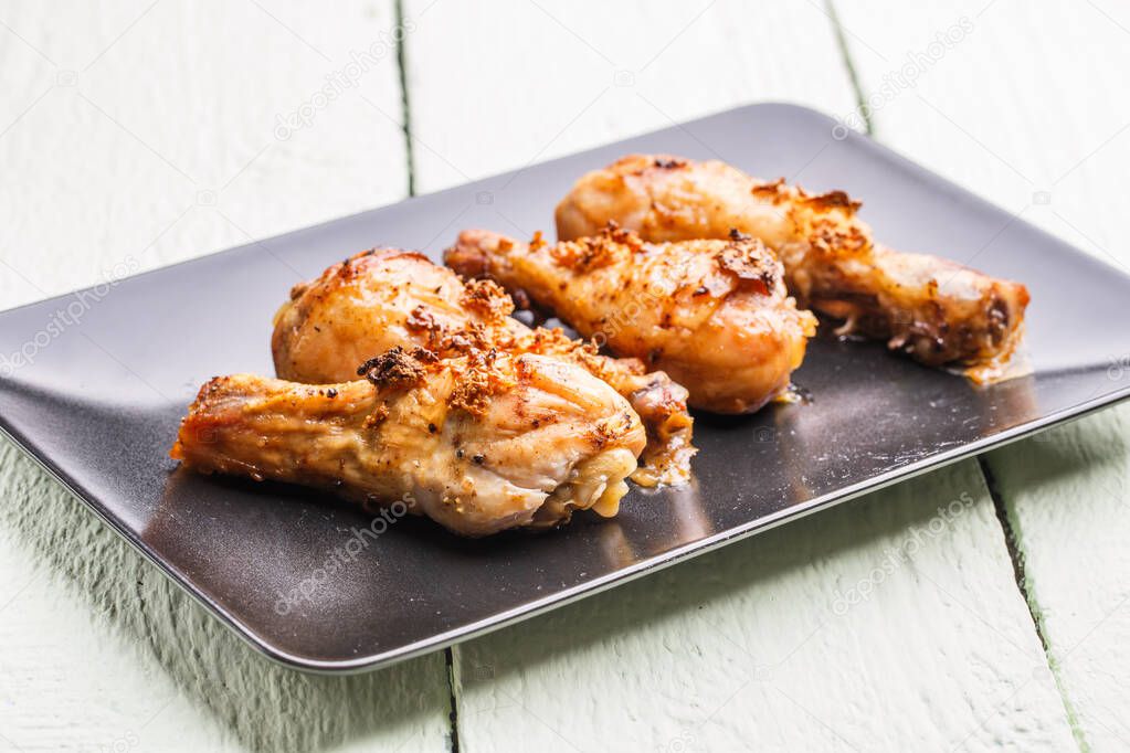 Roasted poultry on black plate at wooden table