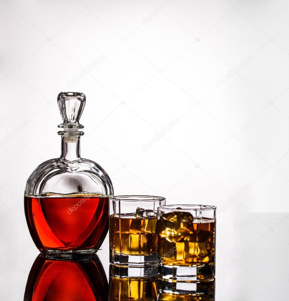 Decanter, two glasses of alcohol and ice on gray background, photo in studio