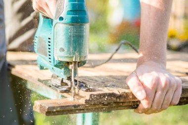 Marangoz parkta elektrikli testereyle tahtayı testereyle kesti