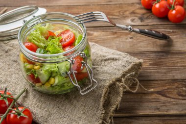 Sebze salatası ve cam kavanoz ve çatal ve temizleme beziyle birlikte mısır.