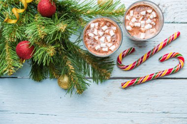 İki bardak marşmelovlu kakao ve beyaz ahşap arka planda oyuncakları olan Noel ağacı. Yukarıdan görüntüle