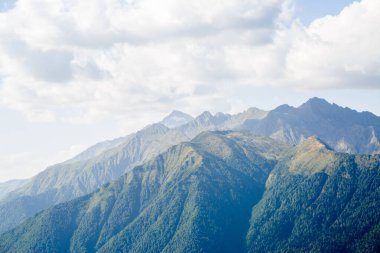 Bulutlu mavi gökyüzüne karşı resim gibi dağlık bir alan