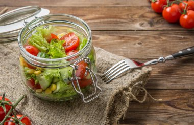 Masada temiz bez, domates ve çatallı taze sebzelerden oluşan faydalı bir akşam yemeği.