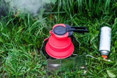 Turist ekipmanı konsepti. Çürütülebilir su kaynayan çaydanlık yanan sobanın üzerinde duruyor..