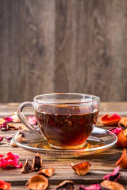 Masada gül yaprakları ve çaydanlıkla şeffaf bir fincan çay.