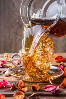 Kahverengi arka planda cam bardakta siyah çay.