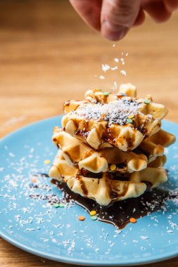 İnsan ev yapımı waffle 'lar serper. Hindistan cevizi. Aşçılık arkaplanı.