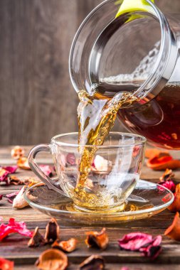 Siyah çay fincana döküldü, masanın üzerine yapraklarla.