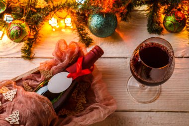 Köknar dalları, Noel baloları, yanan çelenkler, beyaz masada bir şişe şarap ve cam.