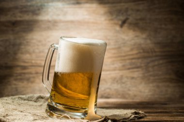 Köpüklü bira bardağa döküldü. Tahta masada duruyordu.