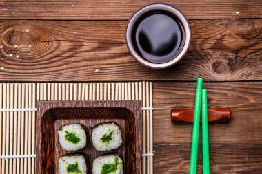 Yuvarlaklar, yeşil çubuklar, bambu peçetedeki sos ahşap masa