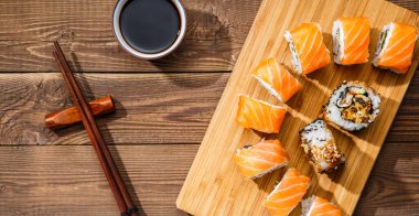 Yemek çubukları ve soya sosuyla ahşap bir tahta üzerinde yuvarlanıyor.