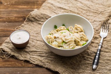 Et hamuru - Rus pelmeni, ahşap arka planda beyaz tabakta etli ravioli.