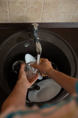 Yukarıdan çekilmiş bir resim. Mutfakta bulaşık yıkıyor.