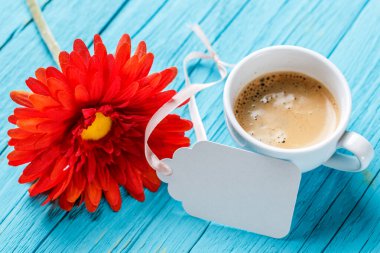 Çiçek, kahve ve kartpostal mavi masada boş.