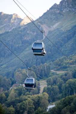 Yaz günü bitki örtüsü arasında dağ tepeleri arasında iki füniküyenin fotoğrafı