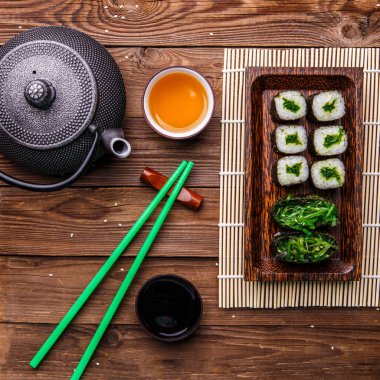 Soya sosu, çay, ahşap yüzeyde bambu peçetede rulo ekmek.