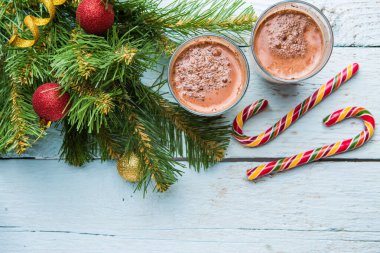 Beyaz ahşap arka planda oyuncakları olan iki bardak kakao ve noel ağacı. Yukarıdan görüntüle