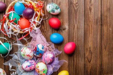 Renkli Paskalya yumurtalarının ahşap masadaki kurdeleli fotoğrafları.