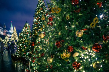 Yılbaşı fotoğrafında koyu mavi gökyüzünün arka planında köknar ağaçları süslenmiş.