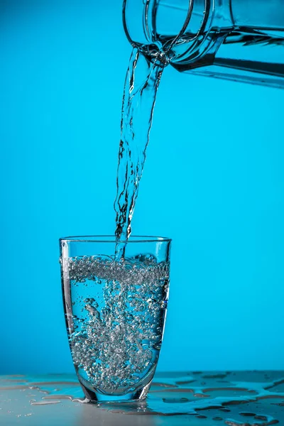 Человек Наливает Воду Стекла Стекло Голубом Фоне Студии — стоковое фото