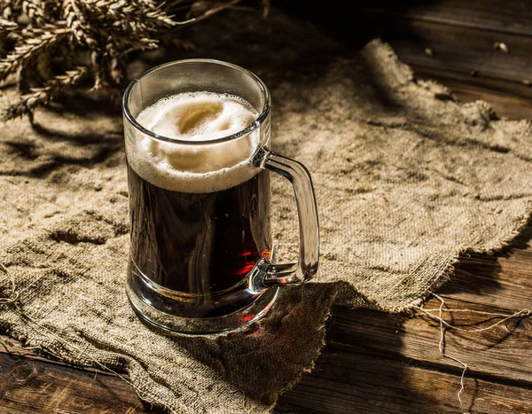 Mug beer with wheat on linen cloth on wooden table