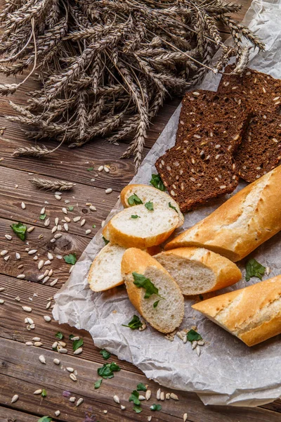 Fresh baguette ,bread with seeds on wooden table with fresh herbs