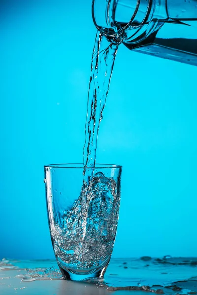 Hombre Vierte Agua Del Vidrio Vidrio Sobre Fondo Azul Estudio —  Fotos de Stock
