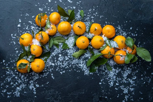 Photo of tangerines on black table with snow