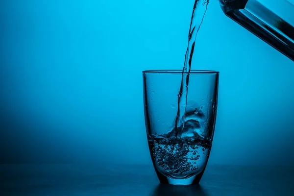 Man Giet Water Uit Glas Glas Blauwe Achtergrond Studio — Stockfoto