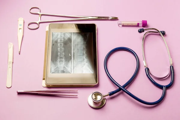 Tablet pc and doctor tools on blue surface. Medical concept